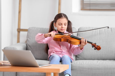 Little girl taking music lessons online at homeの写真素材