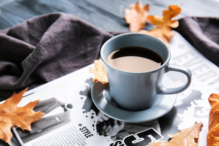 Beautiful autumn composition with cup of coffee and newspaper on table, closeup