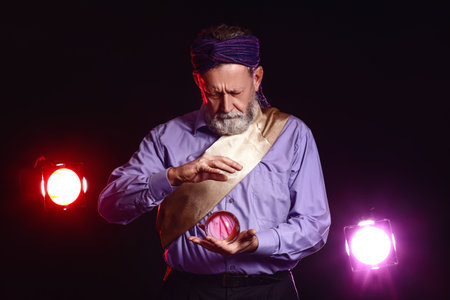 Male fortune teller with crystal ball on dark background