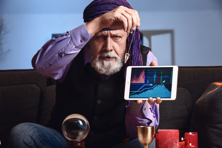Male fortune teller with tablet computer at home