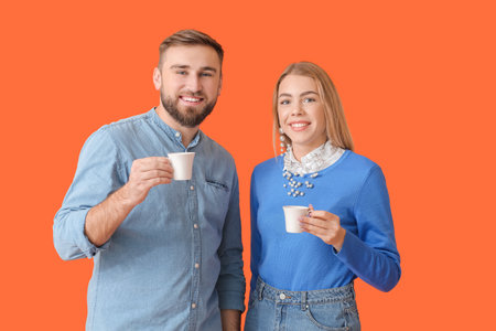 Young couple with hot coffee on color background
