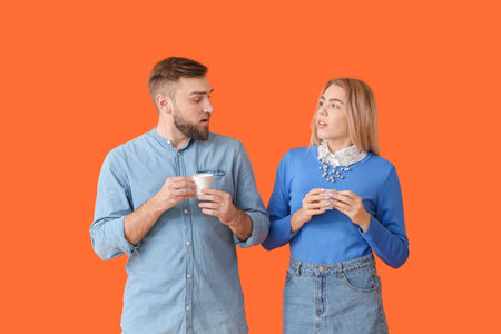 Young couple with hot coffee on color background