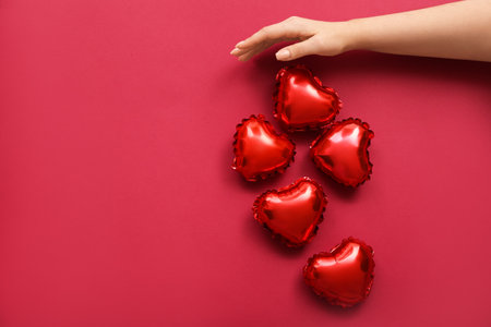 Female hand with small heart shaped balloons on color background. Valentine's Day celebrationの写真素材
