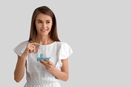 Beautiful woman with container of vitamin supplements on gray backgroundの写真素材