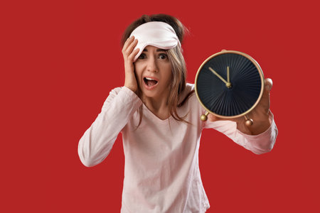Oversleep young woman with alarm clock on red background
