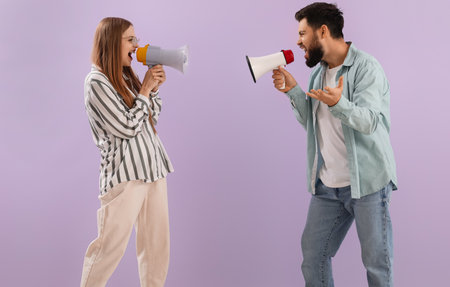 Young couple shouting into megaphones on lilac background