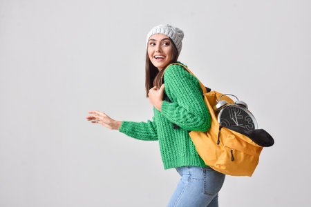 Female student with clock on gray background