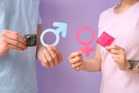 Couple with condoms and symbols of woman and man on color backgroundの素材 [FY310205627369]