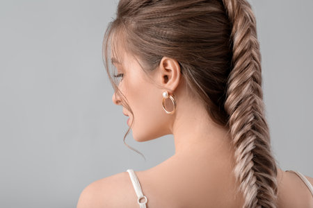 Beautiful young woman with braided hair on gray backgroundの写真素材