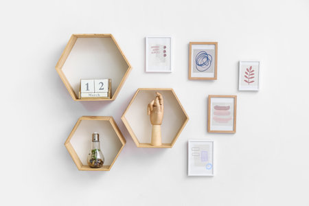 Stylish pictures and shelves with decor hanging on light wallの写真素材
