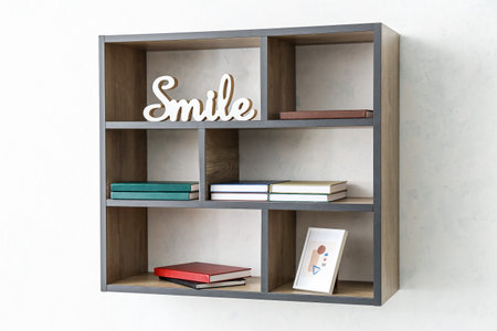 Shelf with books and decor hanging on light wall