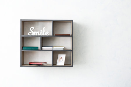 Shelf with books and decor hanging on light wallの写真素材