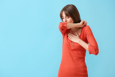 Coughing young woman on color backgroundの写真素材