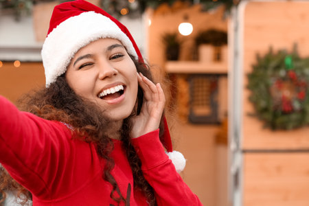 Beautiful young woman taking selfie outdoors on Christmas eveの写真素材