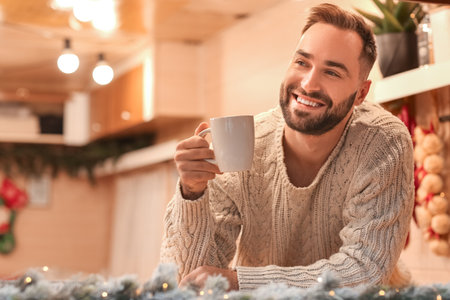 Handsome young man drinking tea at home on Christmas eveの写真素材