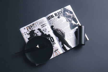 Plate, cutlery and magazine on dark backgroundの写真素材