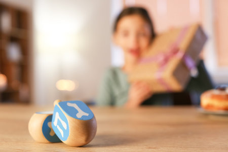 Dreidels for Hannukah on table of happy little girl celebrating Hannukah at homeの写真素材
