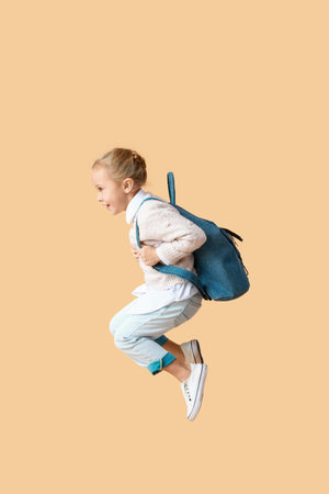 Jumping little schoolgirl on color backgroundの写真素材