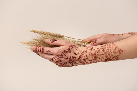 Beautiful female hands with henna tattoo on light backgroundの写真素材