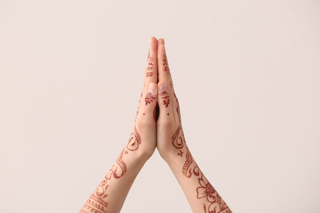 Beautiful female hands with henna tattoo on light backgroundの写真素材