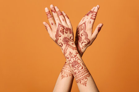 Beautiful female hands with henna tattoo on color backgroundの写真素材