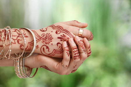 Beautiful woman with henna tattoo on her hands outdoors, closeup