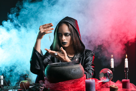 Evil young witch performing ritual on dark backgroundの写真素材