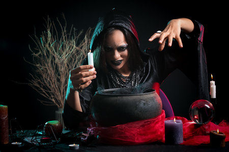 Evil young witch performing ritual on dark backgroundの写真素材