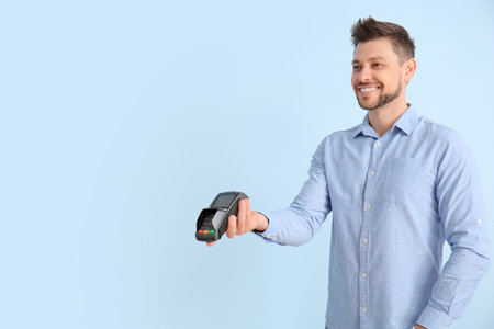 Man with payment terminal on color background