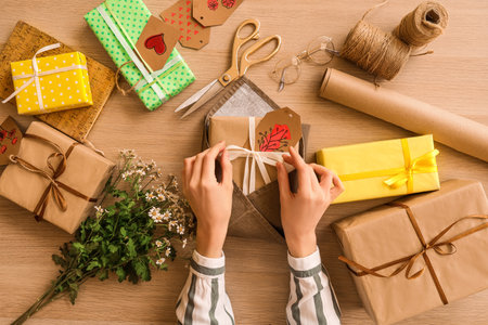Woman with gift boxes and chamomile flowers for International Women's Day on wooden table, top viewの写真素材
