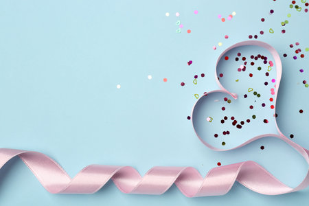 Sequins and heart made of lilac satin ribbon on blue background. Valentine's Day celebrationの写真素材