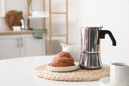 Geyser coffee maker with delicious bun and cup of espresso on table in kitchenの写真素材