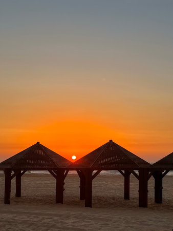 View of sea beach with gazebos at sunsetの写真素材
