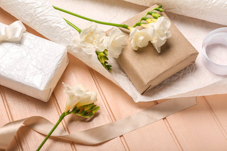 Composition with gift boxes, wrapping paper and beautiful freesia flowers on color wooden background, closeup. Women's Day celebrationの写真素材
