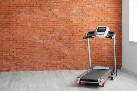 Interior of room with modern treadmill near brick wallの写真素材
