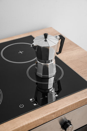 Geyser coffee maker on electric stove in kitchen near gray wallの写真素材