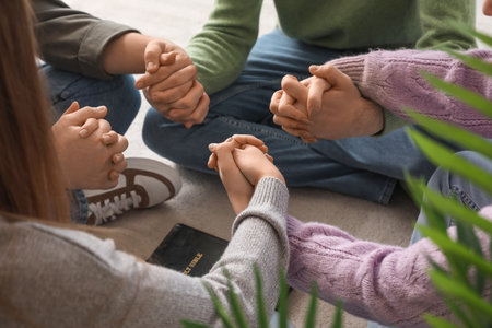 Group of people praying with Holy Bible at home, closeup