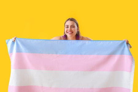 Young woman with transgender flag on yellow backgroundの写真素材