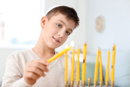 Happy boy lighting candles for celebrating Hannukah at homeの写真素材