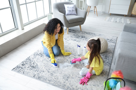 Mother and daughter cleaning carpet at homeの写真素材