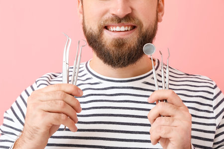 Young man with dental tools on color background, closeupの写真素材