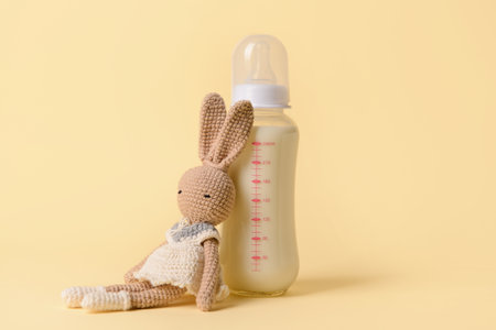 Bottle of milk for baby and toy on color backgroundの写真素材