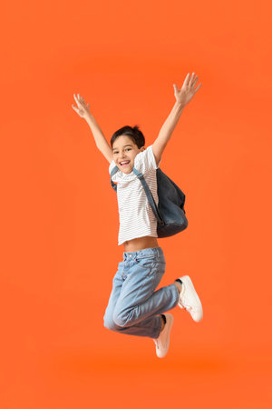 Jumping little schoolboy on color background
