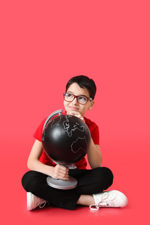 Thoughtful little boy with globe on color backgroundの写真素材