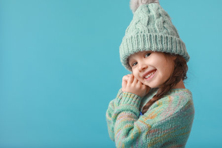 Stylish little girl in winter clothes on color backgroundの写真素材