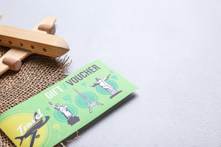 Travel gift voucher, hat and wooden airplane on light backgroundの写真素材