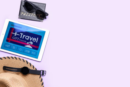 Tablet computer with gift voucher and travel items on light backgroundの写真素材