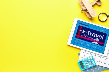 Tablet computer with gift voucher and travel accessories on color backgroundの写真素材