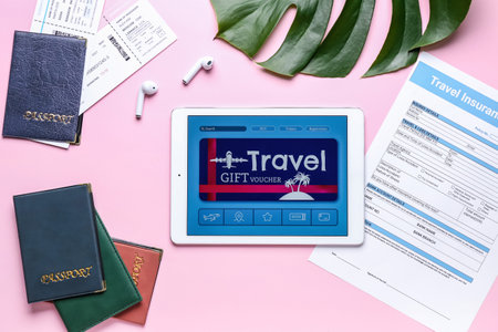 Tablet computer with gift voucher and travel accessories on color backgroundの写真素材