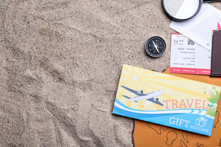 Set of travel items and gift voucher on sandの写真素材